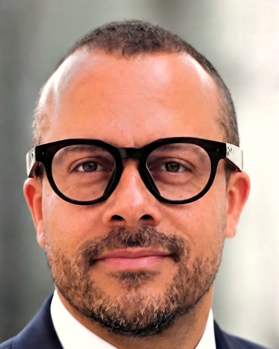 Anton Alexander Palmer in close portrait, wearing round dark-framed glasses